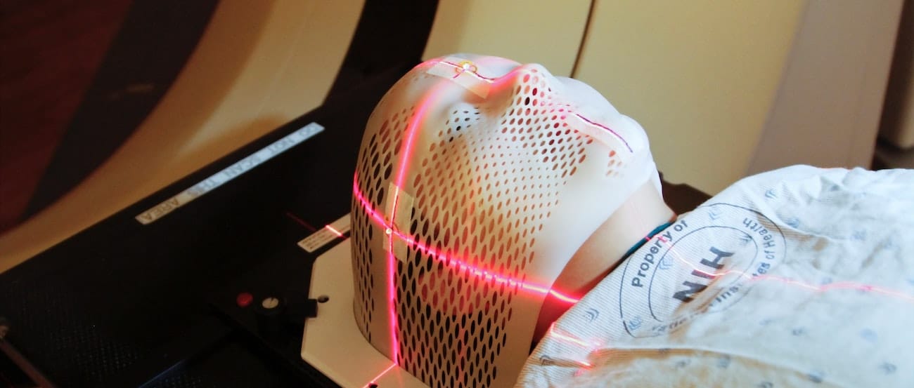 Lasers are used to position a patient model wearing a short face mask in a computed tomography (CT) scanner to obtain images of a tumor